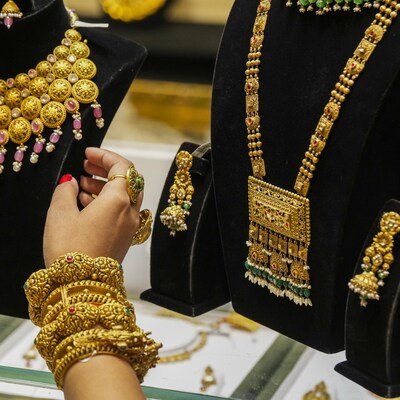 Gold biscuits and sovereign coins on a dark background showcasing Kerala gold rate updates.